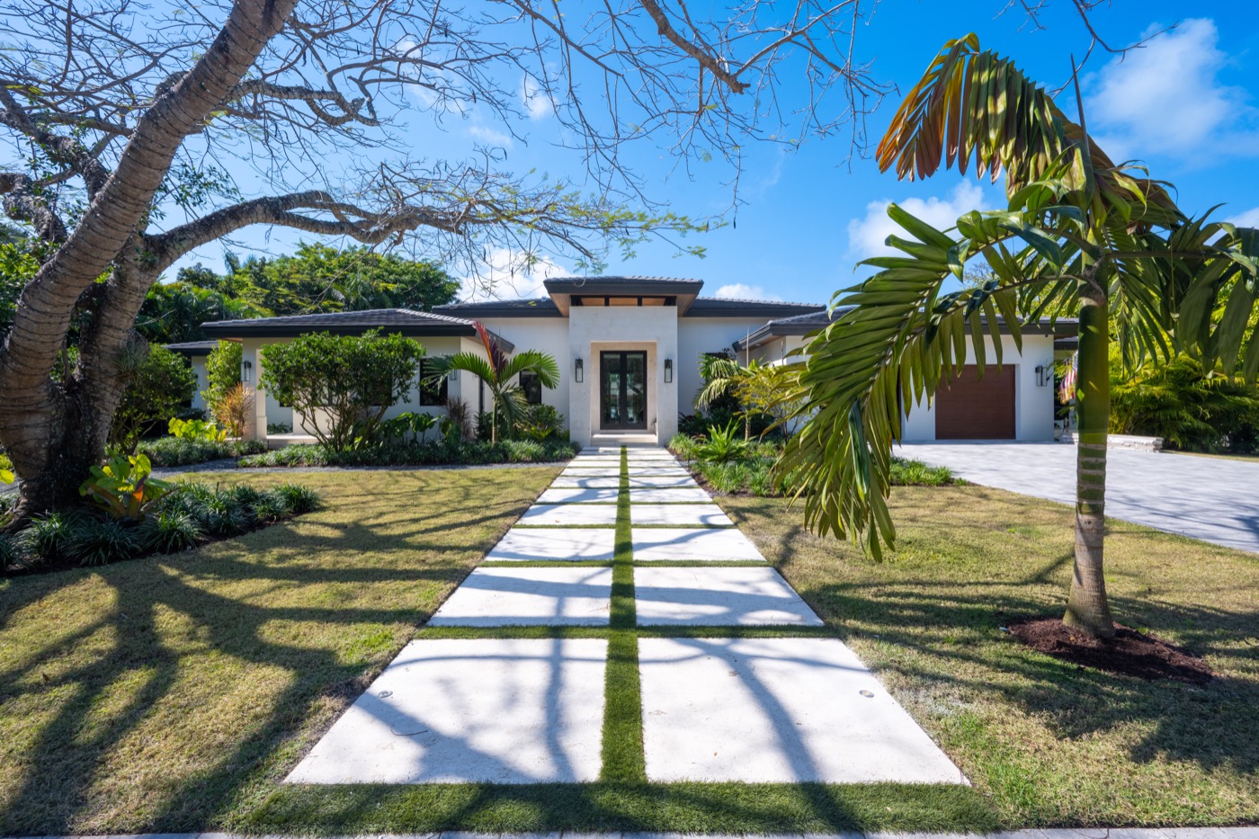 Custom home exterior built by Hereu's Construction, with palm-lined walkway